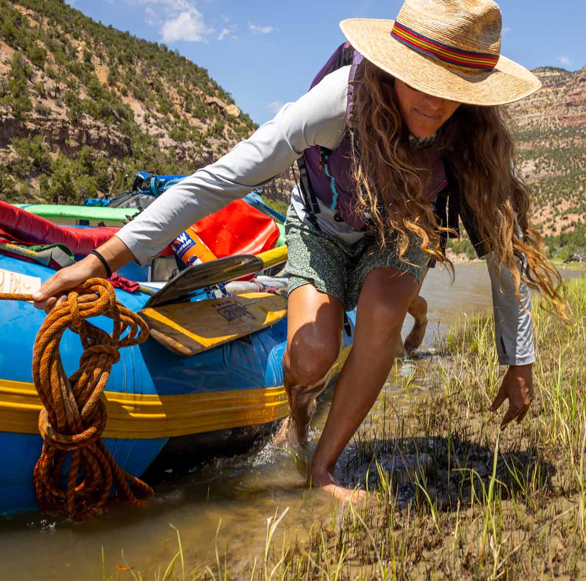 A person pulls a raft onto a riverbank.