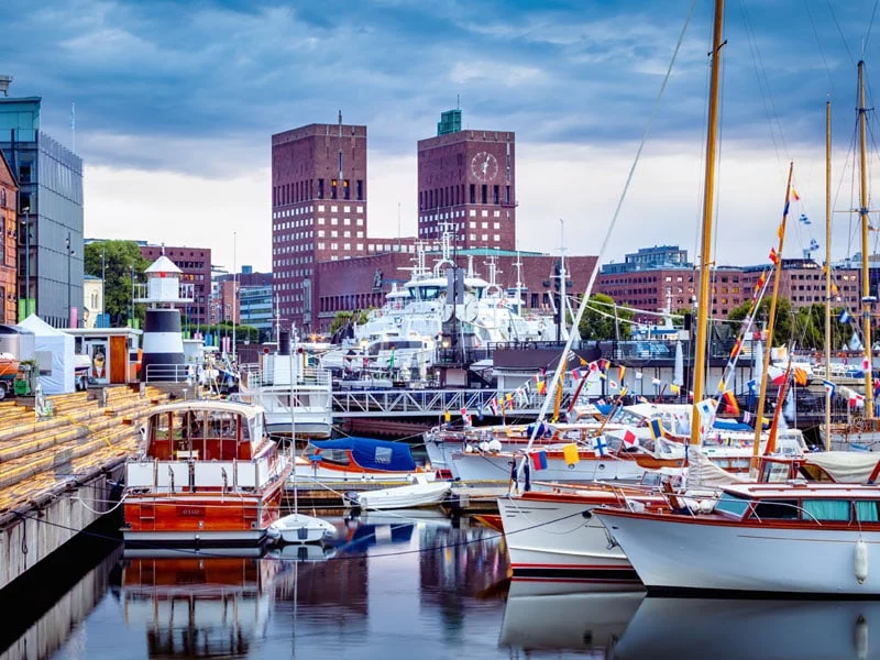 View of Oslo City Hall from Aker Brygge Marina in Oslo, Norway, with boats in the foreground.