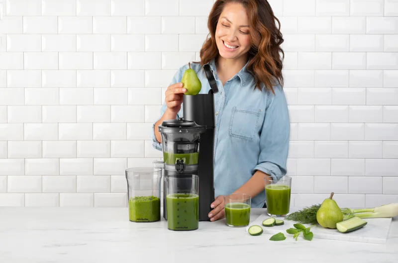 A woman making a green smoothie with the nutribullet Slow Juicer.