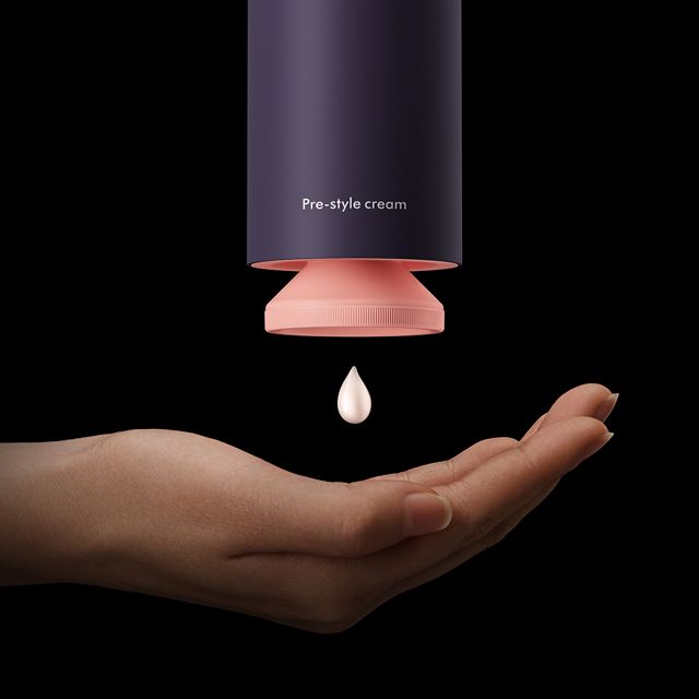 A drop of Dyson Chitosan Pre-style cream is dispensed into a hand.
