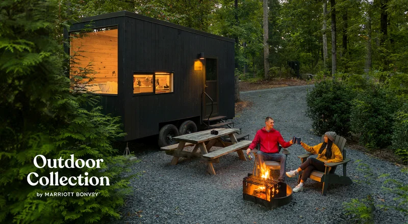 A couple sitting outside by a firepit at an Outdoor Collection by Marriott Bonvoy property.