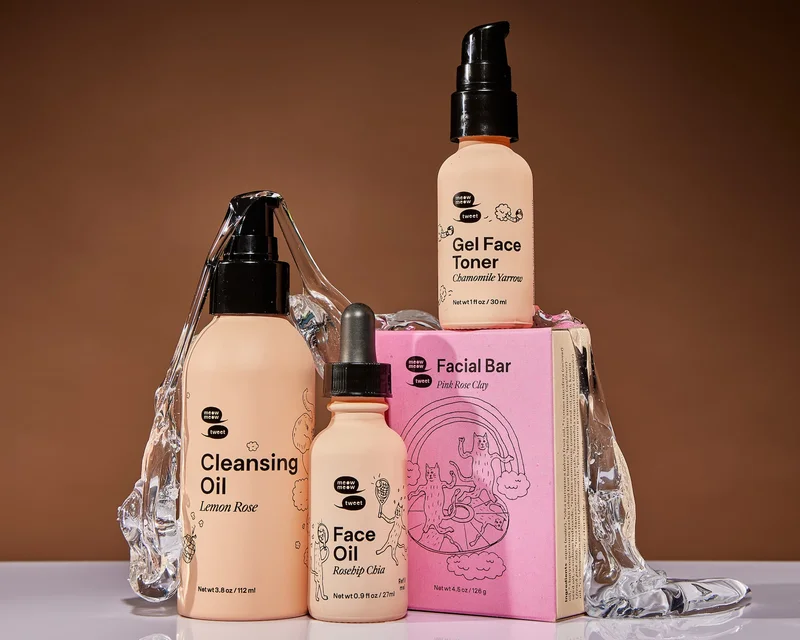 Four skincare products in various pink packaging is displayed against a brown background with clear goop oozing down the products.