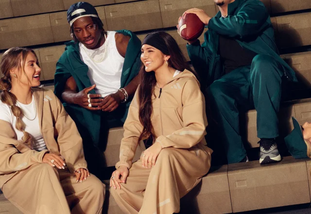 A group of young people sit on the steps of an indoor gym, wearing apparel from the new ADIDAS Z.N.E. range.