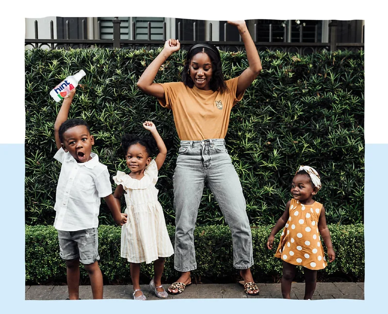 Mom and 3 children dancing holding a Hint bottle