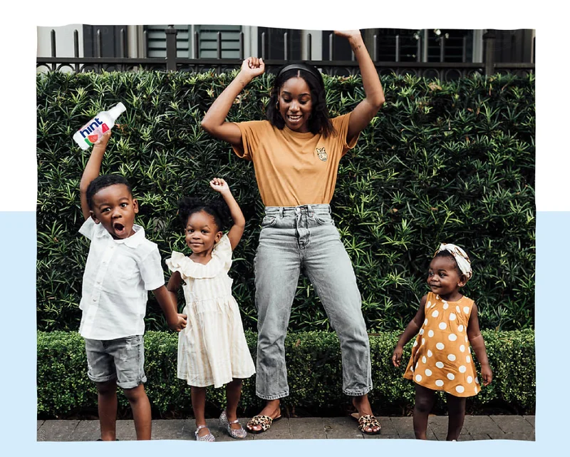 Mom and 3 children dancing holding a Hint bottle