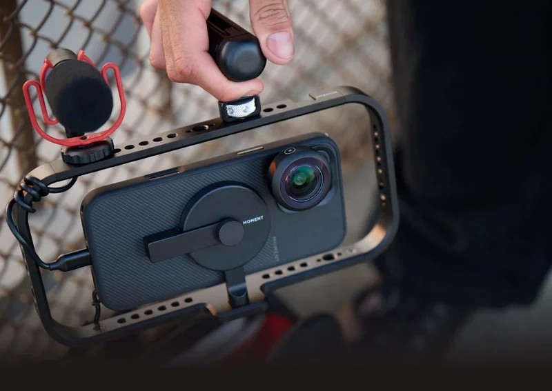 Image of a phone in a moment filmmaker cage with a microphone and single handle.