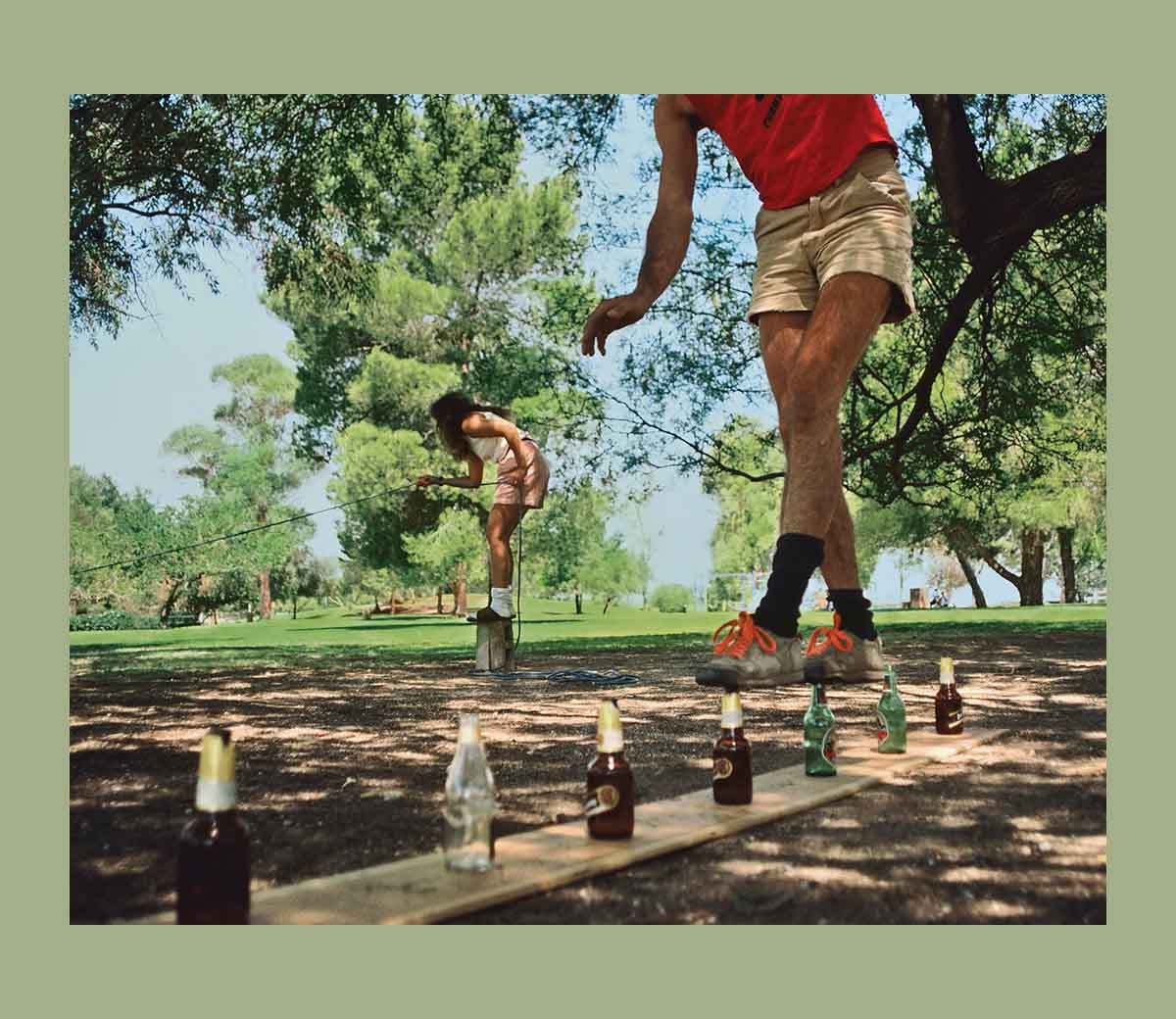 A person attempts to walk across a row of empty beer bottles.