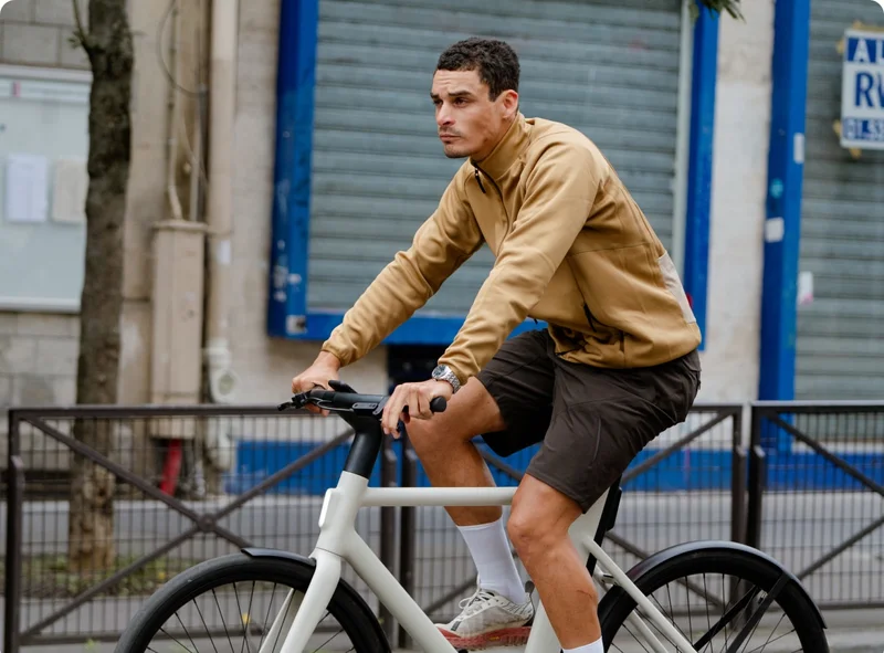 A man wearing Rapha apparel riding a Cowboy Cruiser in Sand
