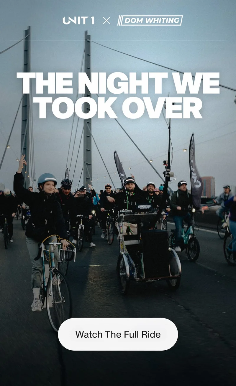 Group of cyclists riding together across a bridge in Düsseldorf during UNIT 1 x Dom Whiting night ride