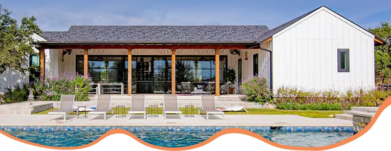 Pool in front of a single-story home with a covered patio, glass windows, and lounge chairs.