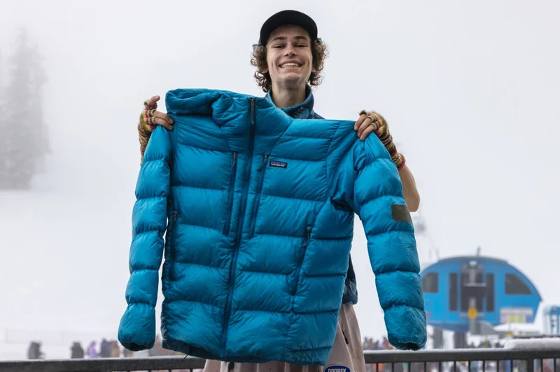 A person smiles while holding up their recently repaired jacket.
