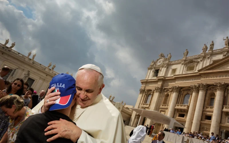 Pope Francis embraces a disabled youth in front of St. Peter’s Basilica.