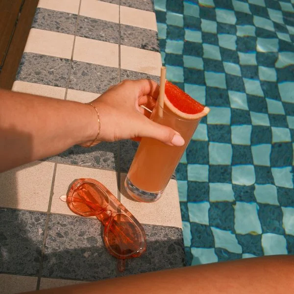 Hand holding drink by pool