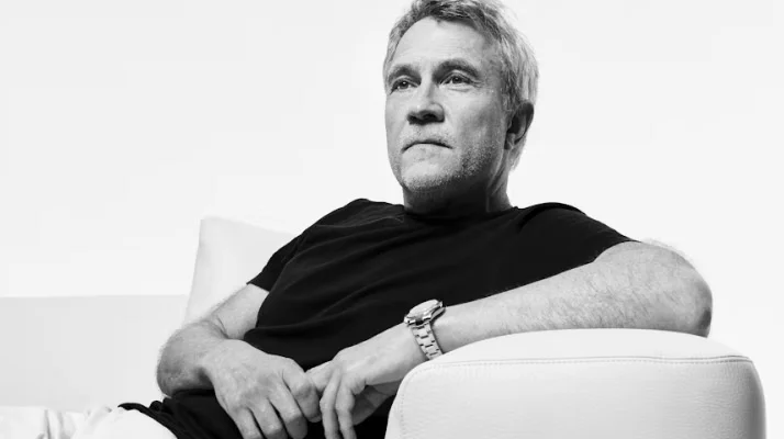 Black and white photo portrait of designer Matthew Hilton, seated in a lounge chair wearing a black t-shirt.