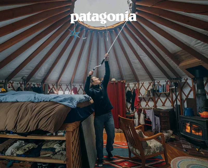 Patagonia. A person uses a long tool to open the roof vent in their yurt.