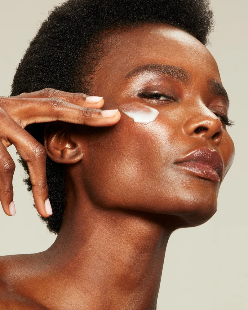 Beautiful woman swiping microcurrent activator across her cheekbone.
