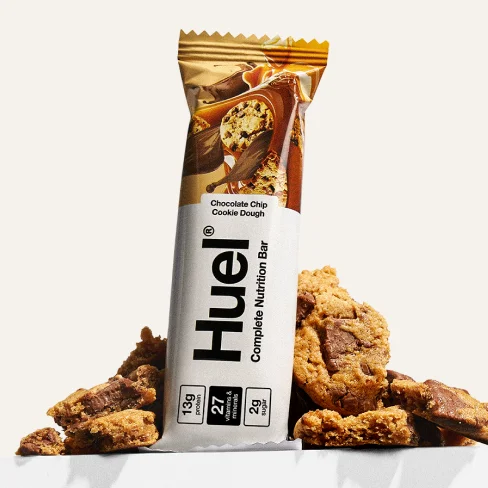Huel Complete Protein Bar with cookie pieces around it