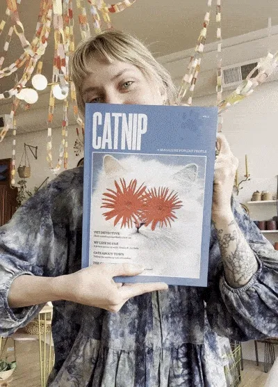A person opens and closes the a magazine with a cat on the cover.