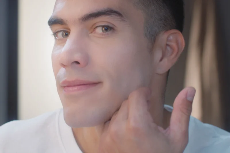 Man touching his freshly shaven face Man touching his freshly shaven face