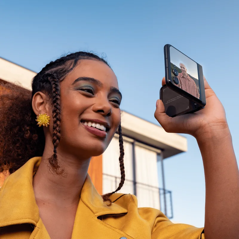 A person smiling and taking a picture with the motorola razr - 2024