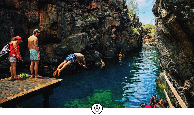 Image Description: People standing on a dock and diving into a lagoon.
