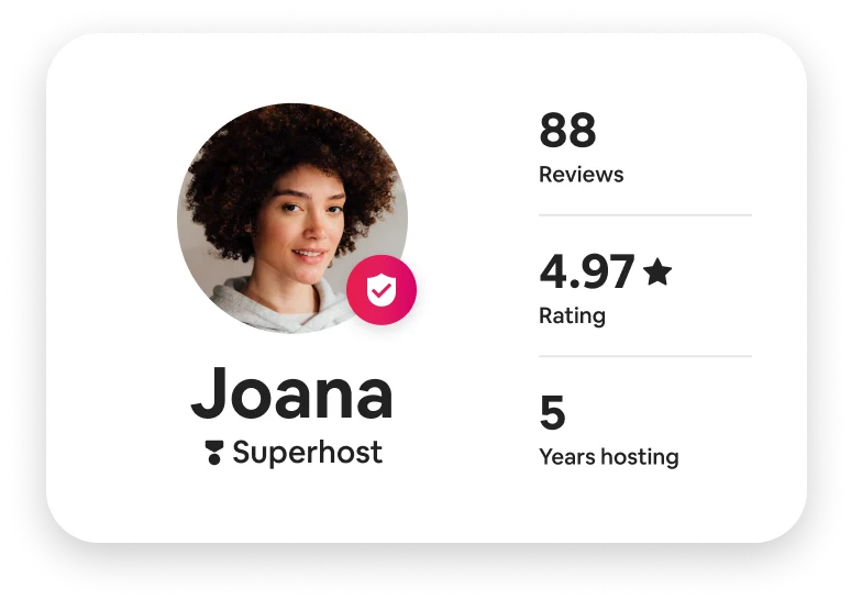 A circular profile picture of a woman with thick, dark, curly hair. Overlapping is an icon of a badge with a check mark. Her name is Joana and she has the title of Superhost. Her profile shows 88 reviews with an average 4.97 stars. She’s been hosting for 5 years.
