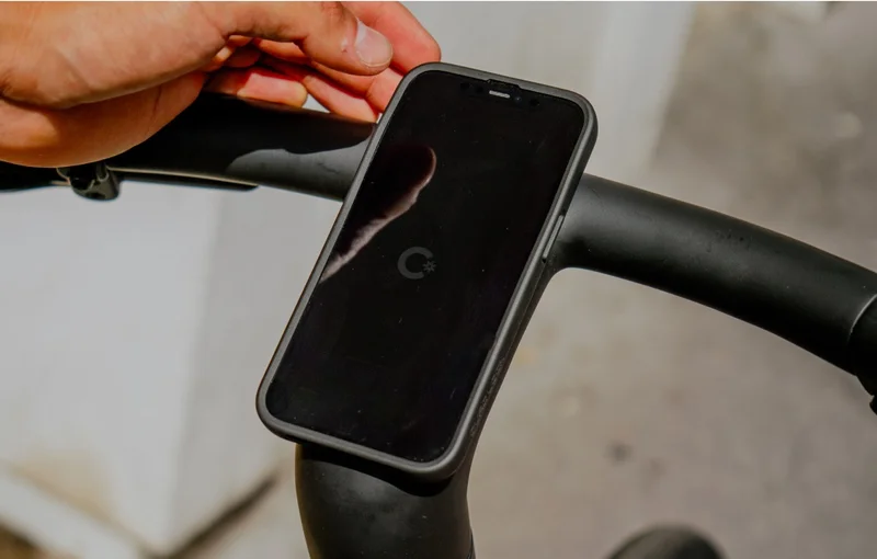 A photograph. A smartphone is mounted to a Cowboy crossbar using a Quadlock case.