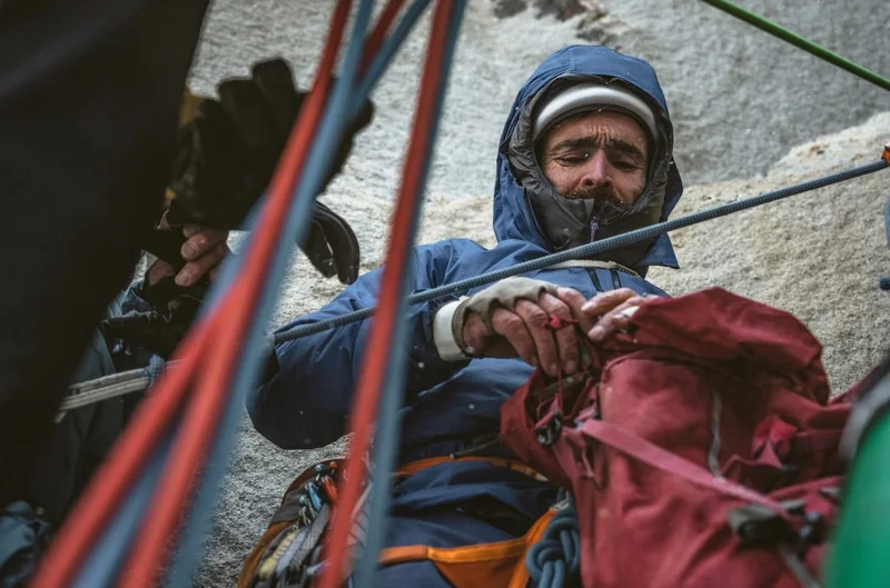 A climber digs through their pack on a big wall.