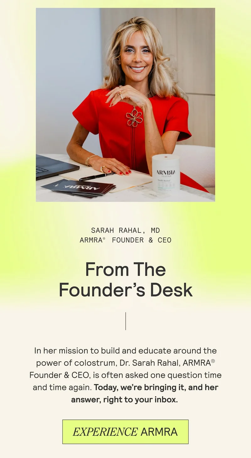 Dr. Sarah Rahal, ARMRA Founder and CEO, smiling at her desk wearing a red dress with ARMRA product and laptop in view.