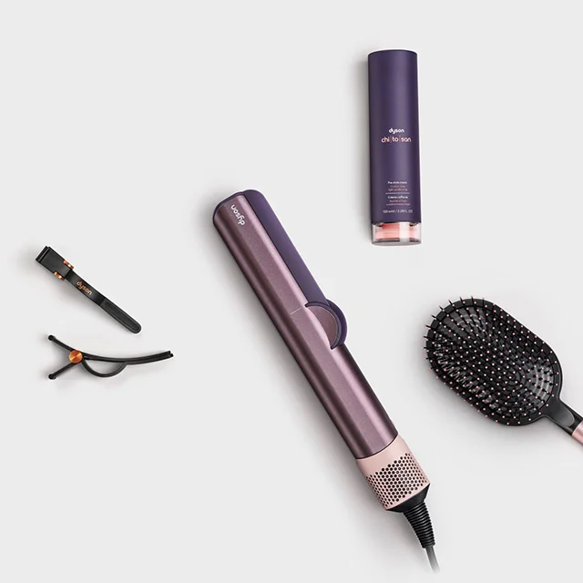 The Dyson Airstrait hair straightener surrounded by attachments and accessories