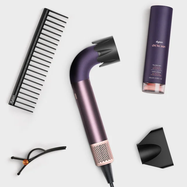 The Dyson Supersonic r hair dryer surrounded by attachments and accessories