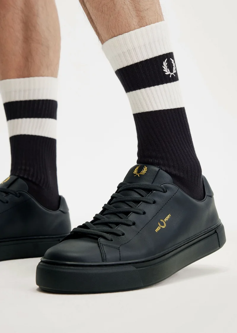 Man wearing stripey Fred Perry socks with black Fred Perry tennis shoe