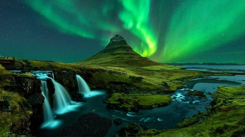 Image description: Northern lights over Mount Kirkjufell and Kirkjufellfoss Waterfall in Iceland.