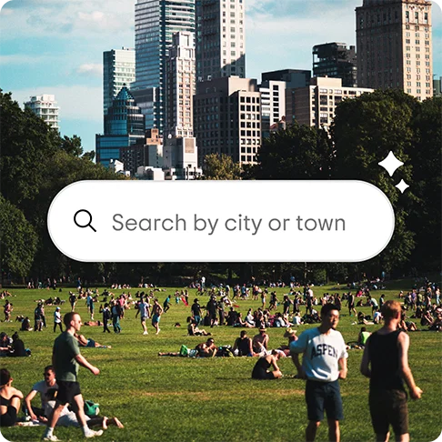Image Description: Central Park filled with people with the city in the background. A graphic search box overlaid says ‘Search by city or town’.