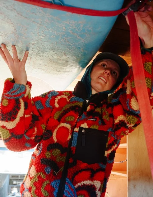 A person loads a surfboard in a van.