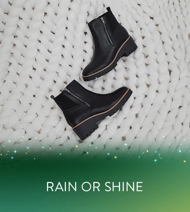 A woman wearing black over-the-knee boots on a rainy street. A pair of black booties.