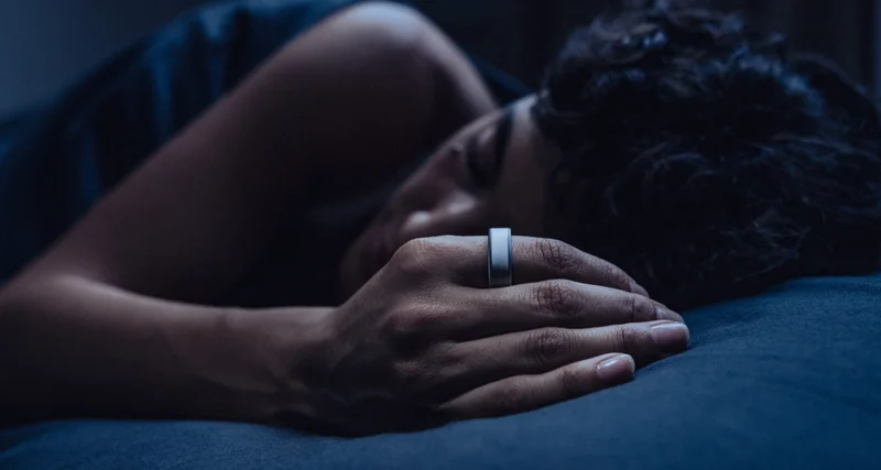 Person sleeping in bed wearing Oura Ring