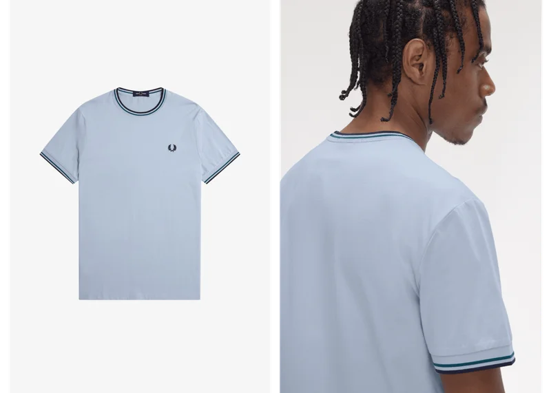 Black male model wears a Fred Perry Twin Tipped T-Shirt in Light Smoke / Petrol Blue / Navy