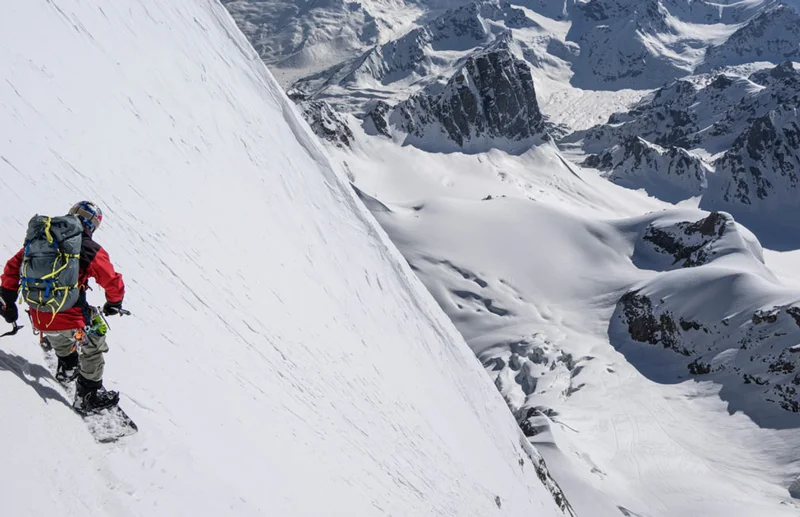 A snowboarder turns on a steep mountainside high in the Himalaya.