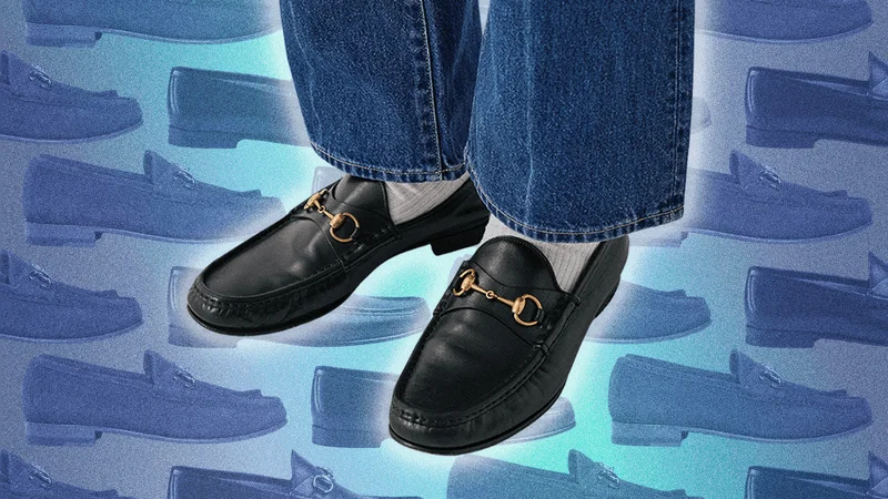 An image of a man's feet in black horsebit loafers, against a blue-tinted background pattern of loafers