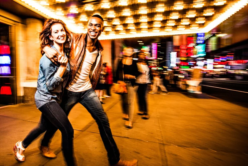 A couple walking under marquee lights on Broadway