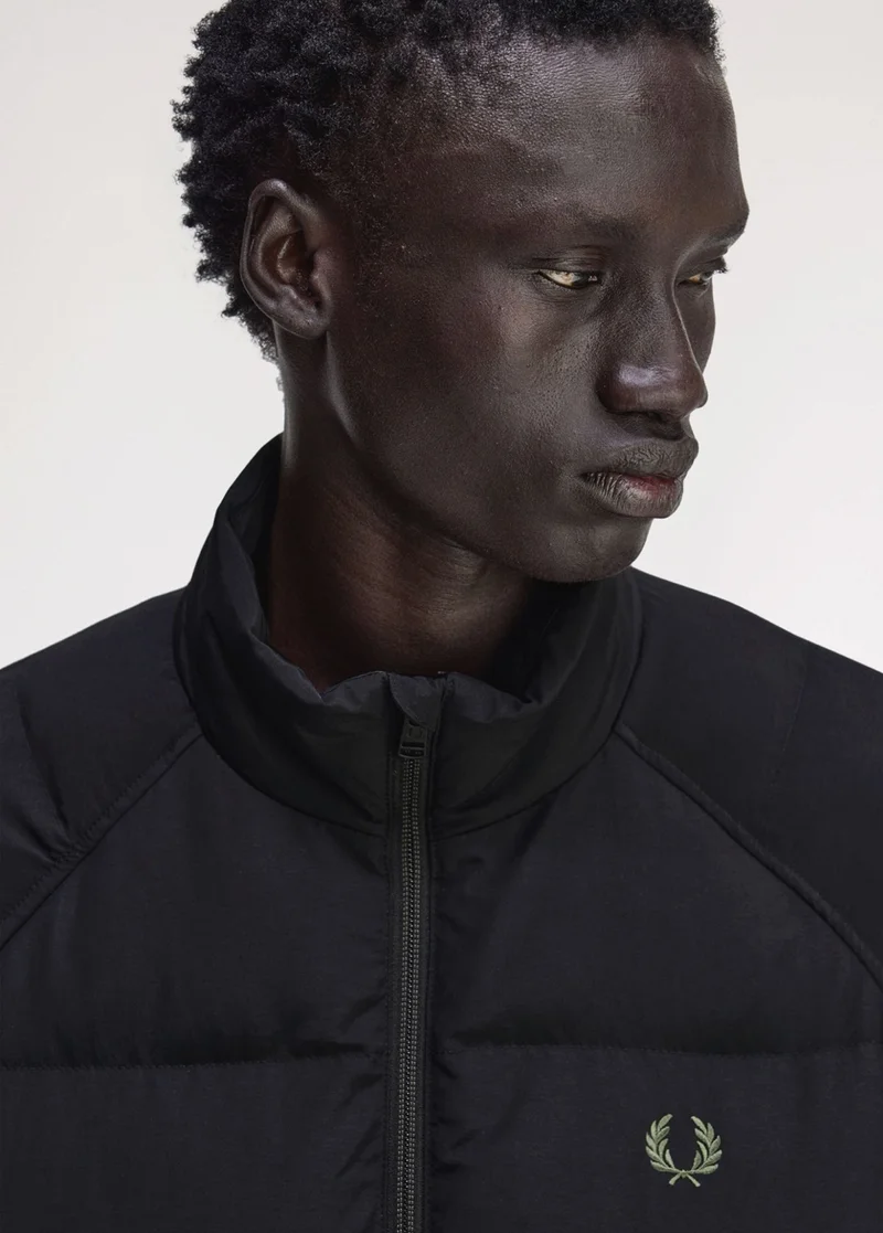 A male model wearing a Fred Perry Raglan Sleeve Padded Jacket in Black