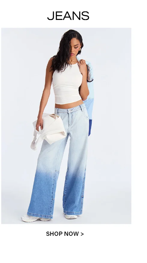 Woman in a white ribbed tank top and stylish light-to-dark blue ombre wide-leg jeans, holding a white bag. Discover new denim styles now.