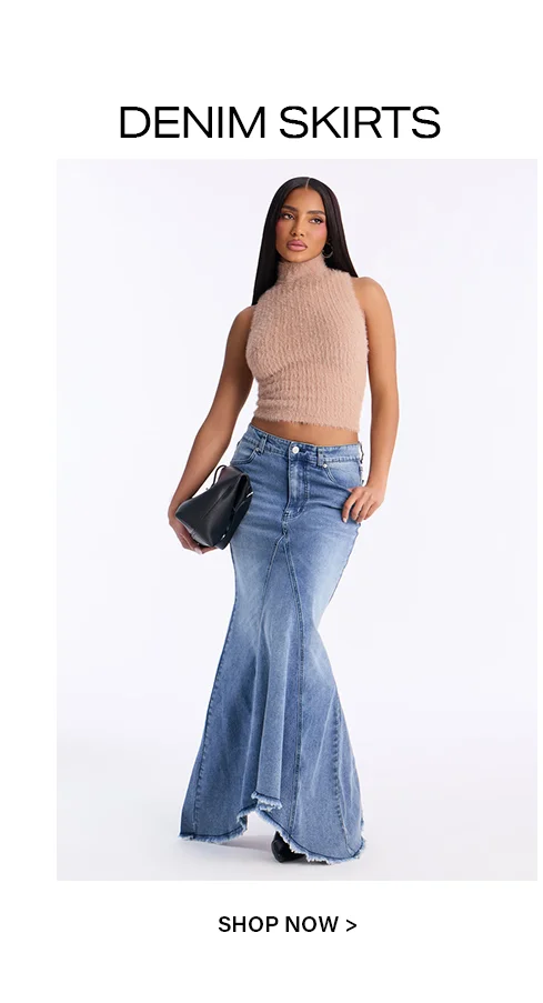 Woman modeling a light blue flared denim maxi skirt with a beige fuzzy crop top and black handbag. Discover our stylish denim skirts now!