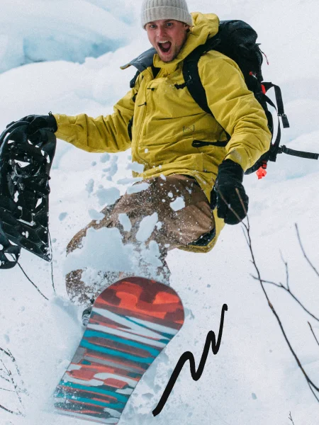 An older model of the Burton Custom Snowboard being ridden in powder