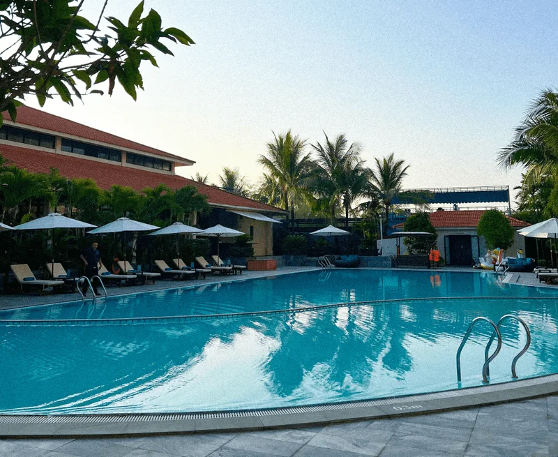 Image description: Hotel pool with lounge chairs and tropical foliage in the background.
