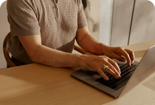 Person typing on a laptop wearing Oura Ring