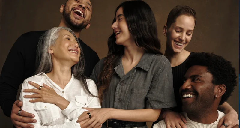 Diverse group of five people smiling and laughing together and wearing Oura Rings