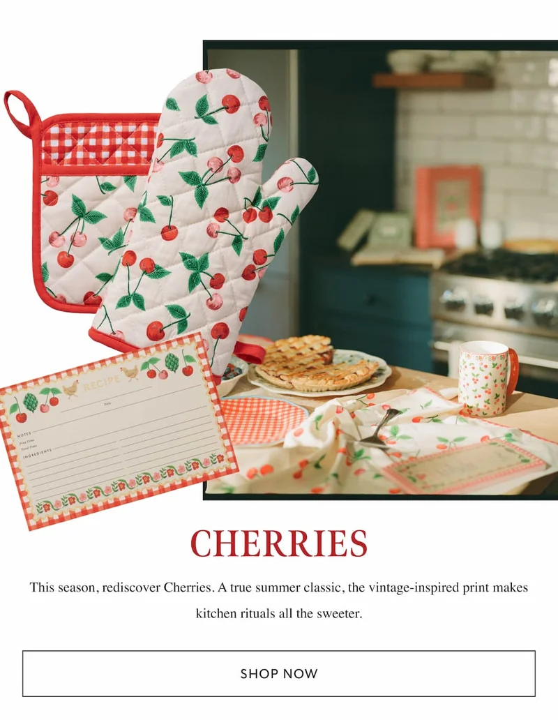 Cherry-themed kitchen items including oven mitt, potholder, recipe cards, and linens, styled with a pie on the counter. "Shop Now" button below.