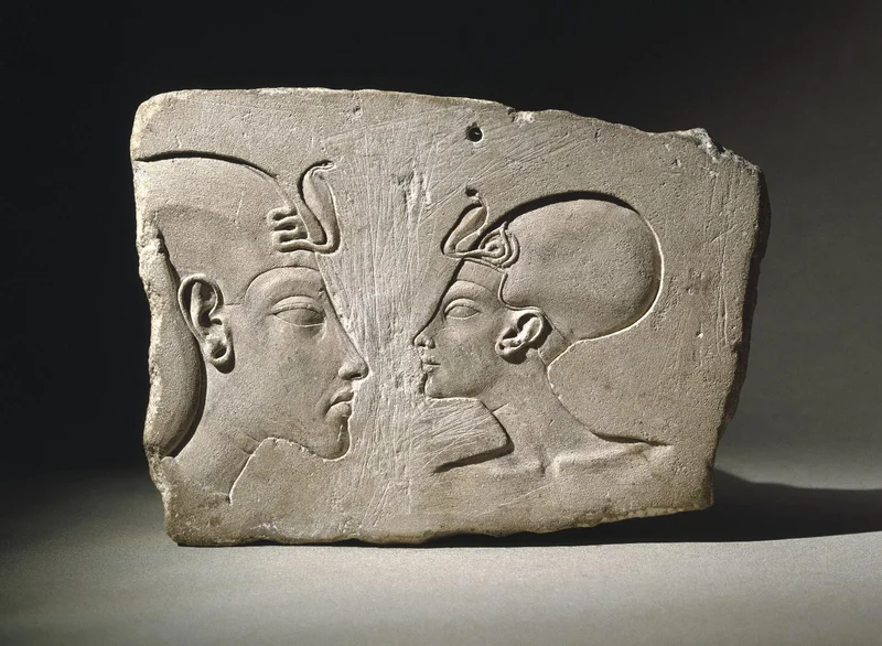 White stone plaque engraved with two heads in profile